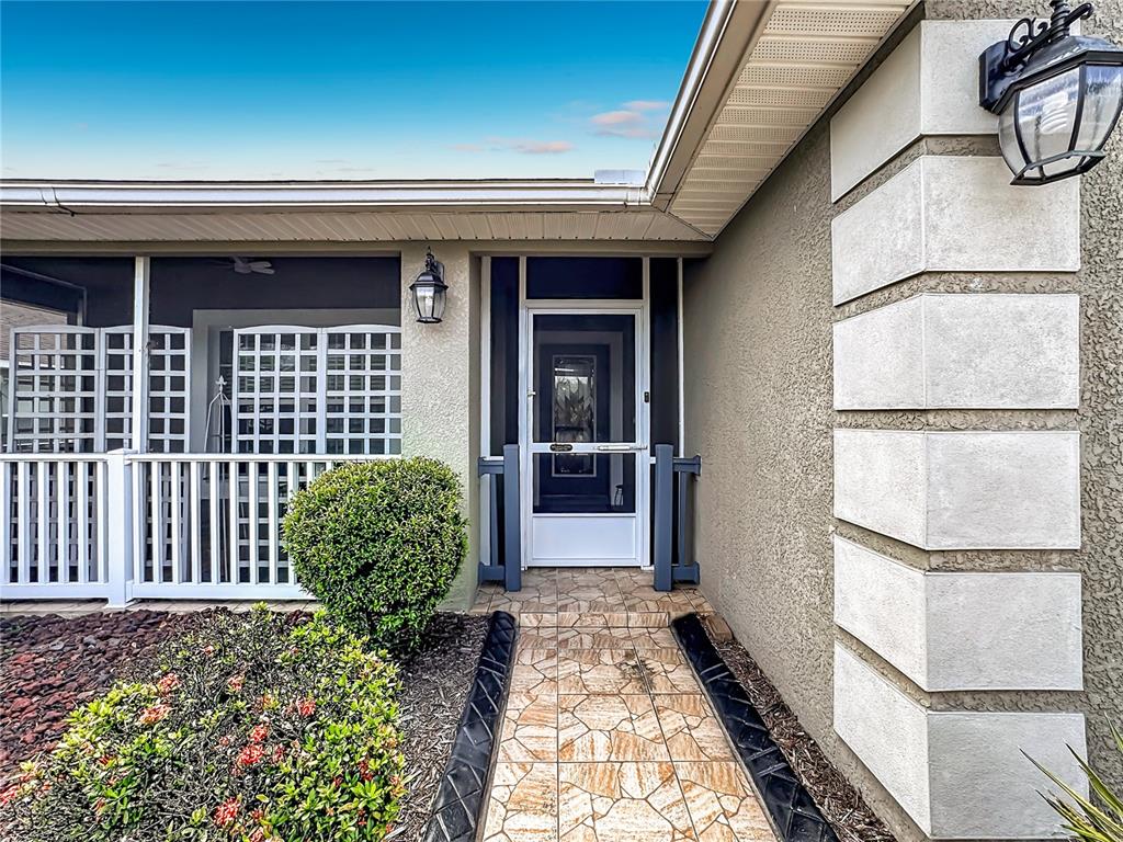 A tiled walkway leads to a front door with a screen door and porch — 10821 STANDING STONE DRIVE, WIMAUMA, FL