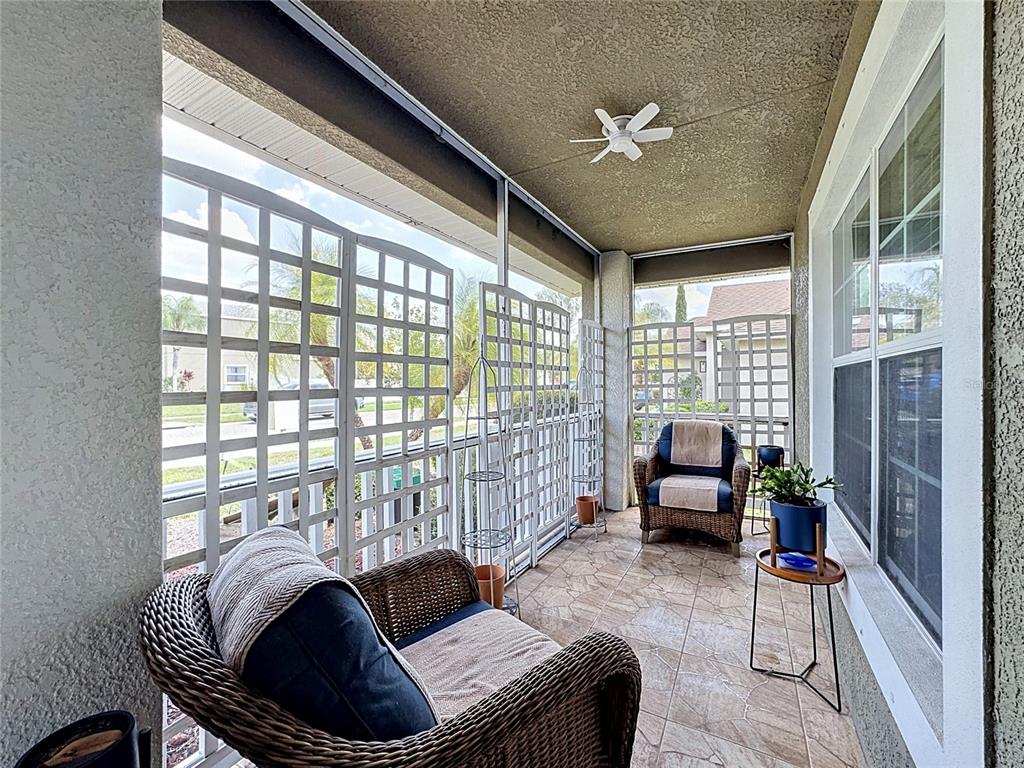 A covered patio features wicker chairs, white lattice privacy screens, and tiled flooring — 10821 STANDING STONE DRIVE, WIMAUMA, FL