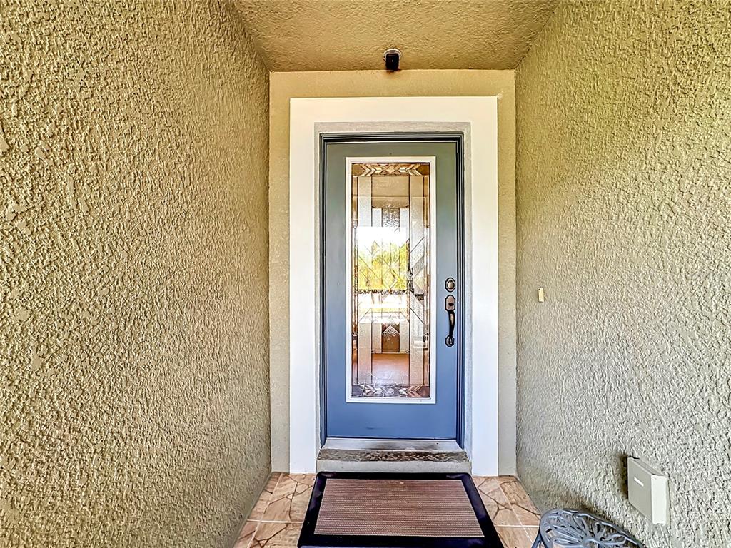 A blue front door with a decorative glass insert is set within a stucco entryway — 10821 STANDING STONE DRIVE, WIMAUMA, FL