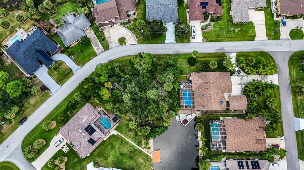 An aerial view shows several suburban houses with swimming pools and a canal — 15 COVINGTON LANE, PALM COAST, FL