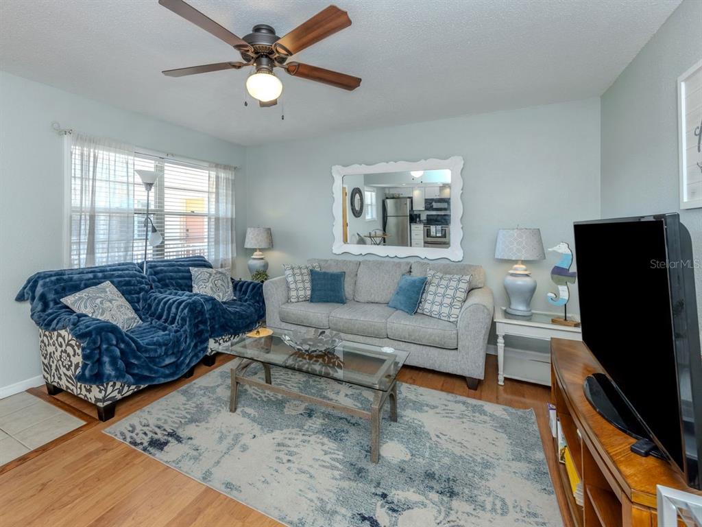 A living room features a blue sofa, a grey sofa, a glass coffee table, and rug — 400 BASE AVENUE E UNIT 227, VENICE, FL