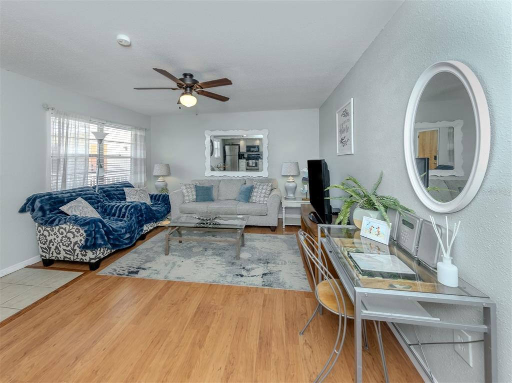 A living room features a blue sofa, a gray sofa, and a glass-topped desk — 400 BASE AVENUE E UNIT 227, VENICE, FL