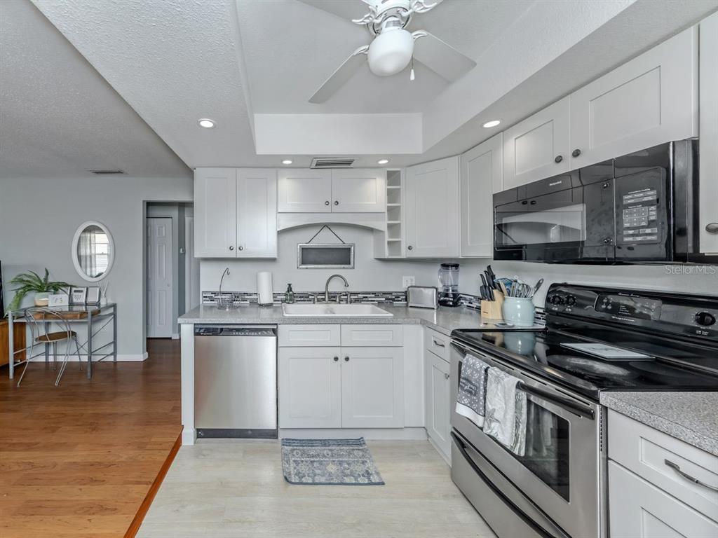 A kitchen features white cabinets, stainless steel appliances, and a light-colored countertop — 400 BASE AVENUE E UNIT 227, VENICE, FL