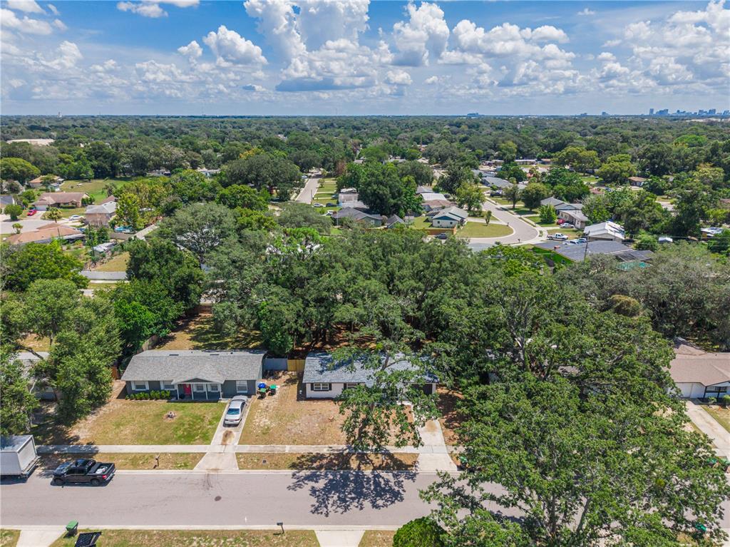 An aerial view shows two single-story houses with driveways surrounded by mature trees and lawns — 3669 YOSEMITE DRIVE, ORLANDO, FL