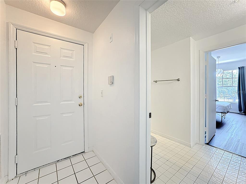 A white front door opens into a tiled entryway with a view into a bedroom — 5548 METROWEST BOULEVARD UNIT 209, ORLANDO, FL