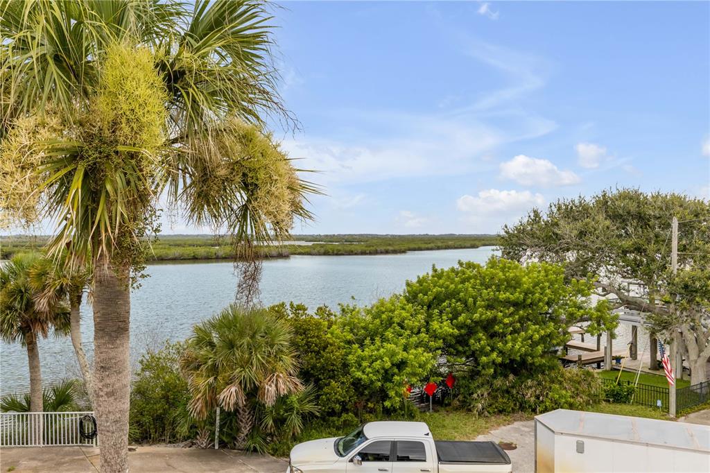 A three-story house with horizontal wood siding, a paved driveway, and a second-story balcony — 830 EEL AVENUE, NEW SMYRNA BEACH, FL