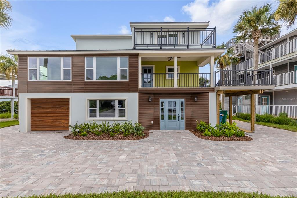 A light blue front door is centered on a brown horizontal-sided wall with stone pavers — 830 EEL AVENUE, NEW SMYRNA BEACH, FL