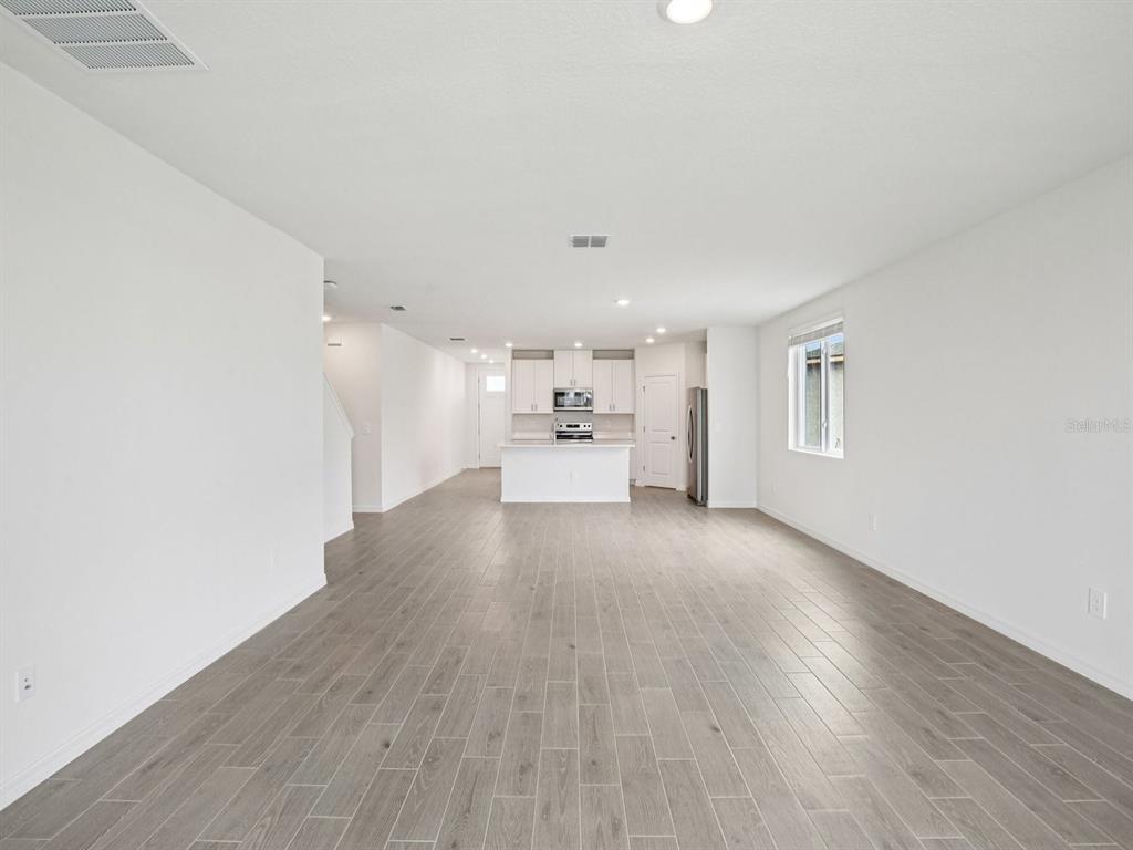 An open-concept living area features light gray wood-look tile flooring and a white kitchen — 7214 RAY CREEK DRIVE, BROOKSVILLE, FL