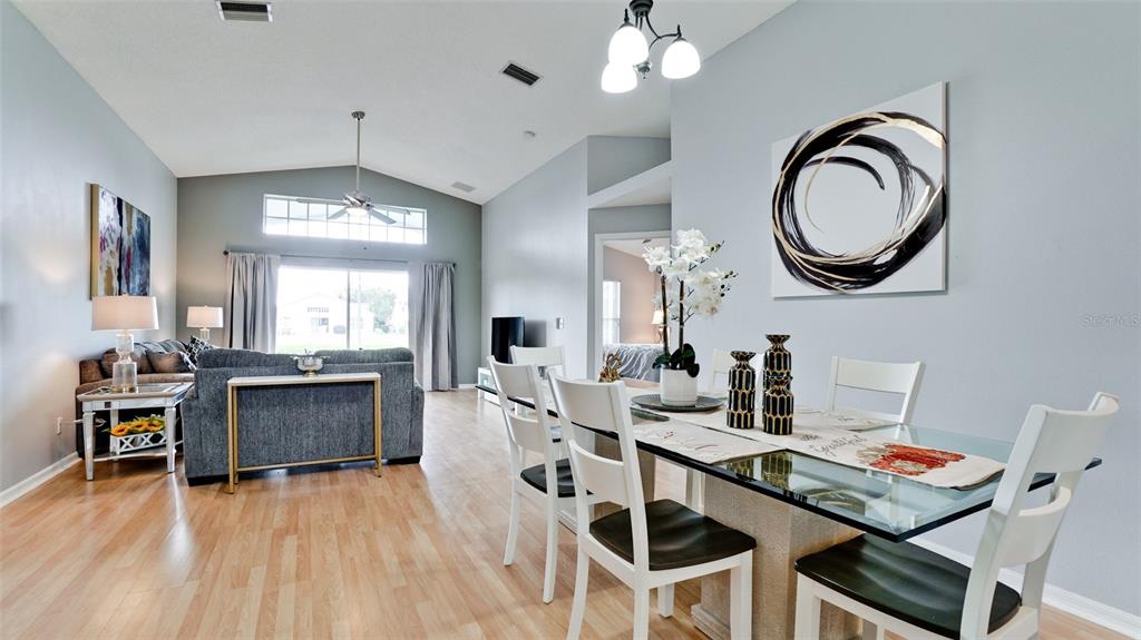A dining area with a glass table sits in front of a living room space — 4584 RUNABOUT WAY, BRADENTON, FL