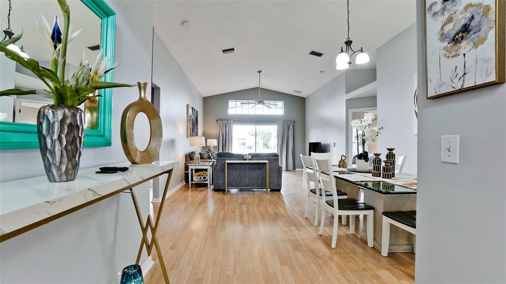 A bright open-concept living and dining area features light wood flooring and vaulted ceilings — 4584 RUNABOUT WAY, BRADENTON, FL