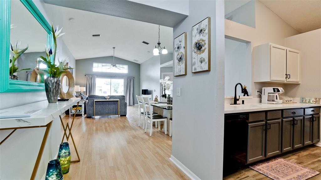 A view from a hallway into a living room and dining area with a wet bar — 4584 RUNABOUT WAY, BRADENTON, FL