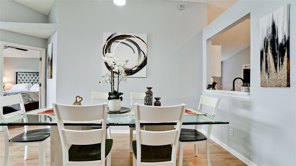 A dining room features a glass-topped table, white chairs, and abstract wall art — 4584 RUNABOUT WAY, BRADENTON, FL
