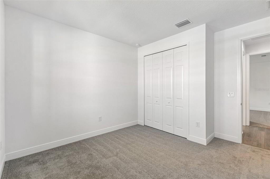 An empty room with white walls, gray carpet, and two windows overlooking a grassy field — 2091 CLARY SAGE DRIVE, SPRING HILL, FL