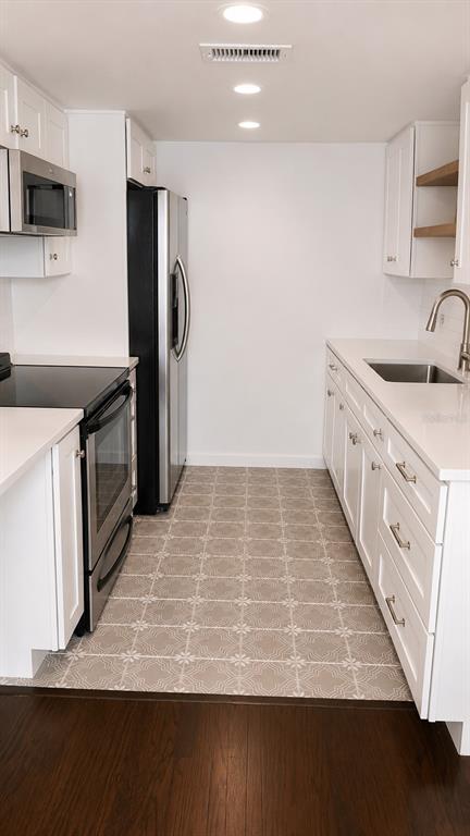 A kitchen with white cabinets, stainless steel appliances, quartz countertops, and patterned tile flooring — 4611 W NORTH B STREET UNIT 232, TAMPA, FL