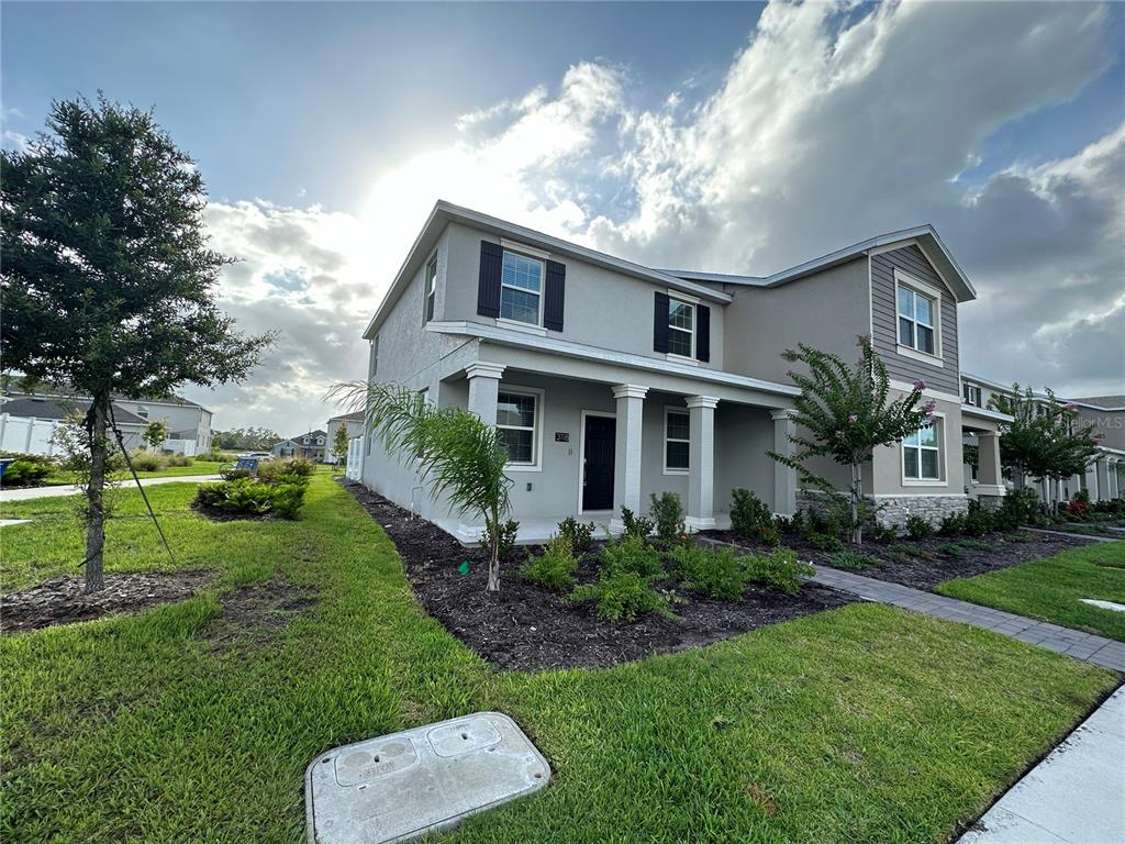 A two-story suburban house features a covered front porch, gray siding, and a landscaped yard — 3118 ADDISON BOULEVARD, ST CLOUD, FL