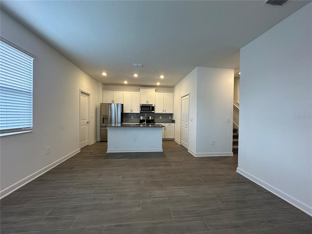A kitchen with white cabinets, stainless steel appliances, and an island sits in an open room — 3118 ADDISON BOULEVARD, ST CLOUD, FL
