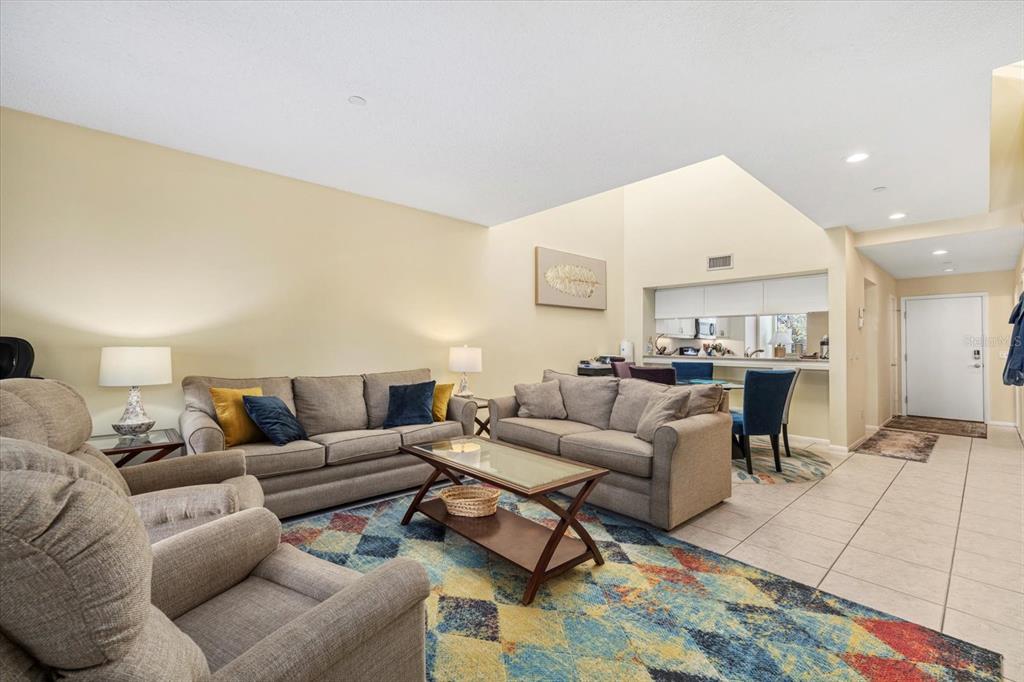 A living room with beige sofas, a patterned rug, and a vaulted ceiling — 2012 HARBOURSIDE DRIVE UNIT 2102, LONGBOAT KEY, FL