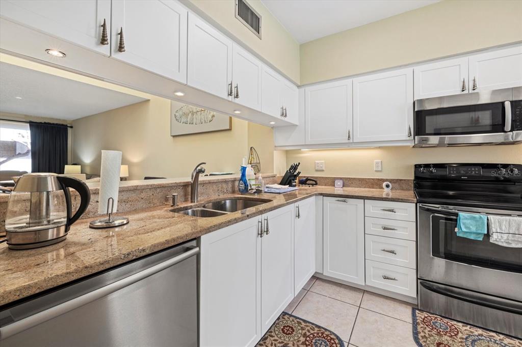 A kitchen features white cabinets, granite countertops, stainless steel appliances, and a double sink — 2012 HARBOURSIDE DRIVE UNIT 2102, LONGBOAT KEY, FL
