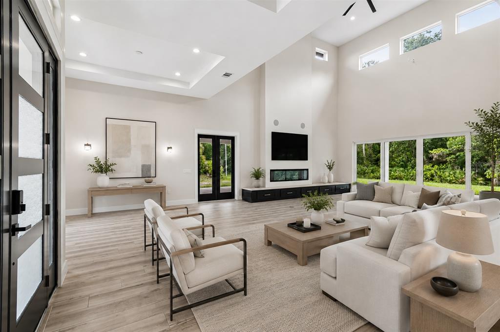 A covered front porch features a double door entrance, a chandelier, and potted ferns — 12000 GOLDEN VALLEY DRIVE, NEW PORT RICHEY, FL