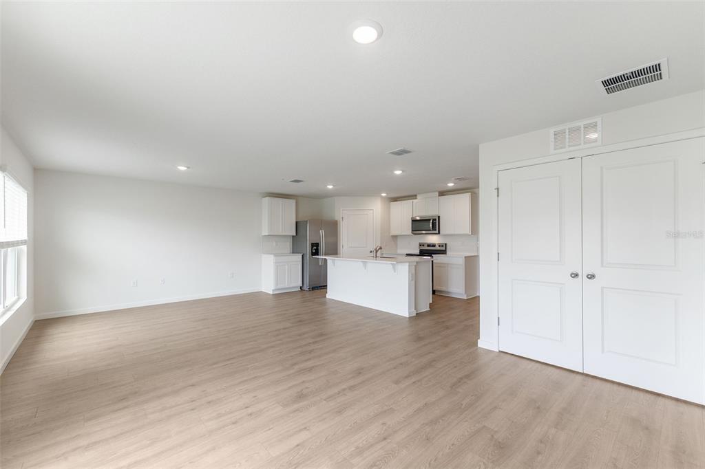 An open-concept kitchen with white cabinetry and an island overlooks a spacious living area — 369 BASS COURT, POINCIANA, FL