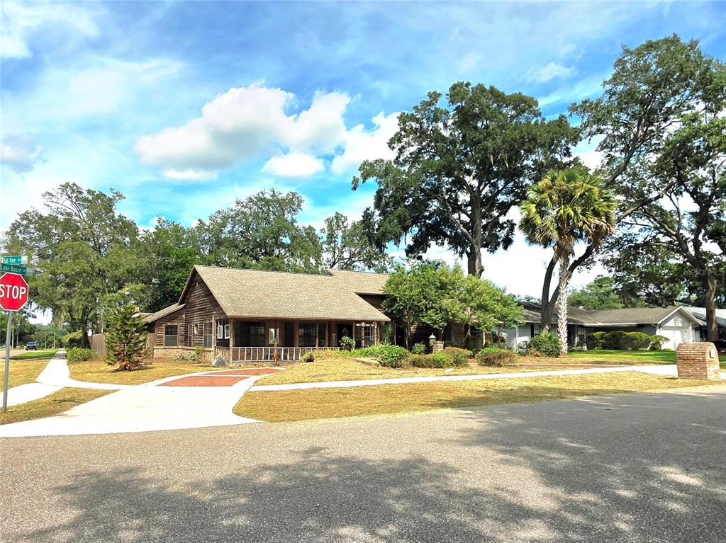 A single-story wooden house with a covered porch sits on a corner lot with trees — 4231 TALL TREE DRIVE, ORLANDO, FL