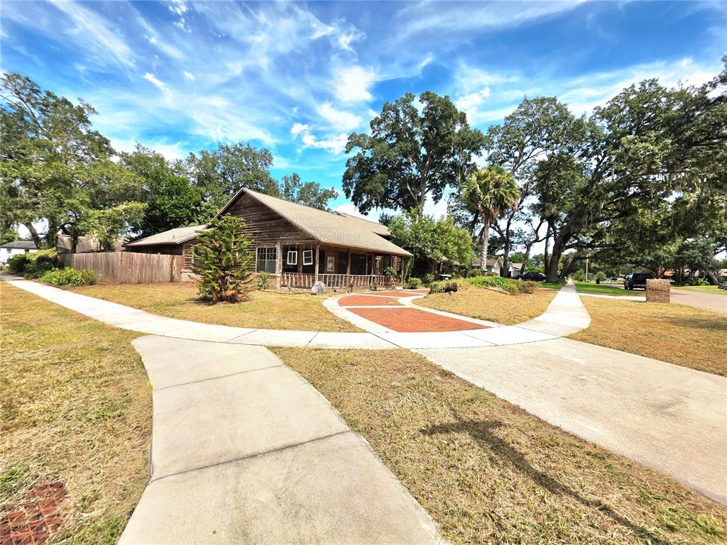 A wooden house with a porch sits behind a concrete walkway and brick path — 4231 TALL TREE DRIVE, ORLANDO, FL