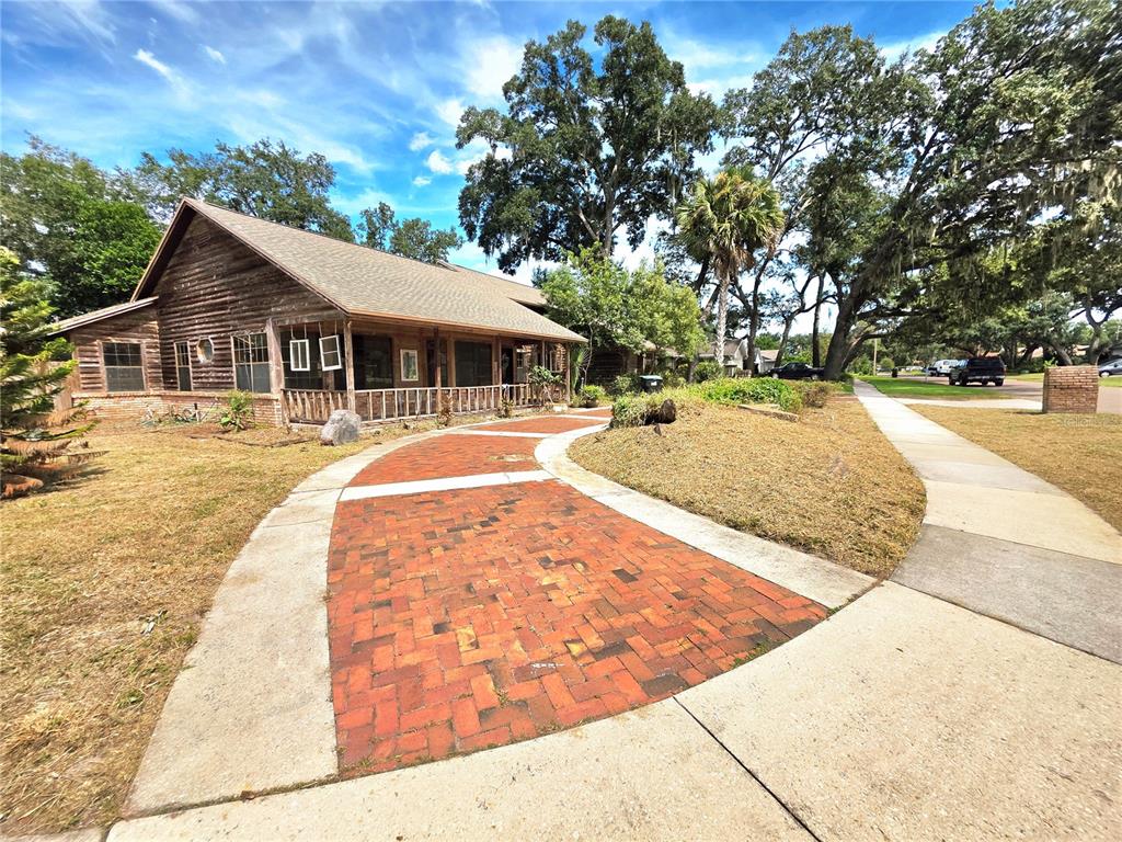 A rustic wooden house with a brick walkway leading to a covered front porch — 4231 TALL TREE DRIVE, ORLANDO, FL