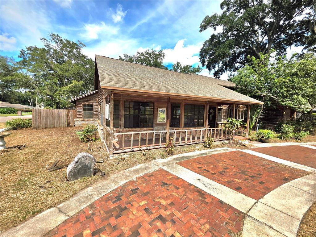 A rustic wooden house features a covered front porch and a brick-paved driveway — 4231 TALL TREE DRIVE, ORLANDO, FL