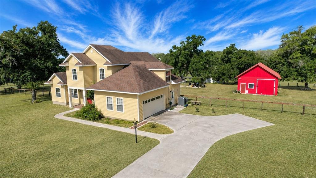 A yellow two-story house with a concrete driveway and a red barn in the yard — 35405 STAGECOACH TRAIL, EUSTIS, FL