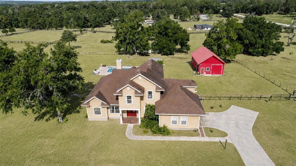 An aerial view of a tan house with a brown roof, pool, and red barn — 35405 STAGECOACH TRAIL, EUSTIS, FL
