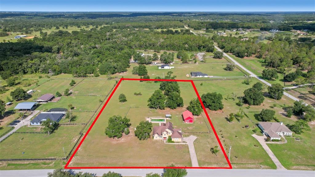 An aerial view shows a house, a red barn, and a pool on a fenced lot — 35405 STAGECOACH TRAIL, EUSTIS, FL
