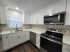 A modern kitchen features white cabinets, stainless steel appliances, and a light-colored countertop — 5903 TOPHER TRAIL UNIT 5903, MULBERRY, FL