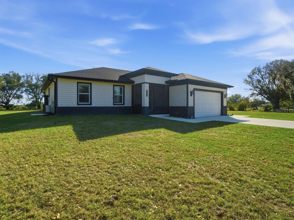 A single-story house with light siding, dark trim, and an attached garage sits on grass — 4135 SW LANGFORD STREET, ARCADIA, FL