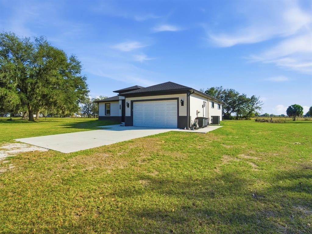 A single-story house with a white exterior, dark trim, and a two-car garage — 4135 SW LANGFORD STREET, ARCADIA, FL