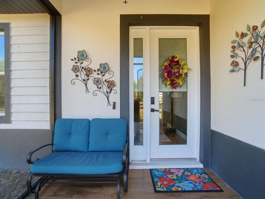A front porch features a blue bench, a floral doormat, and metal wall art — 4135 SW LANGFORD STREET, ARCADIA, FL