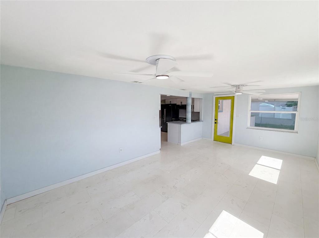 A bright room with white tile floors, light blue walls, two ceiling fans, and a lime-green door — 13638 EVELANE DRIVE, HUDSON, FL