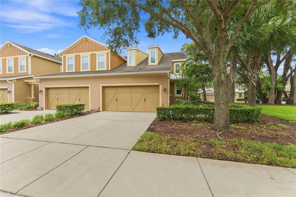 A two-story tan townhouse with a two-car garage and a concrete driveway — 17013 VILESTA DRIVE, LUTZ, FL