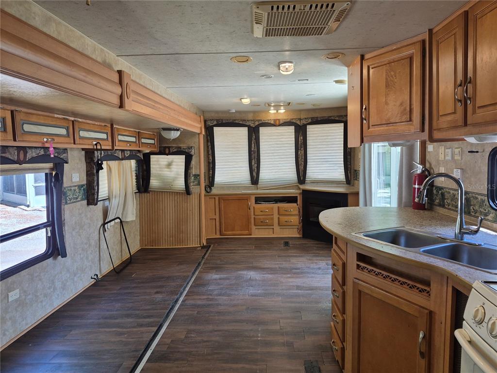 A kitchen with wood cabinets, a white stove, and a refrigerator inside a mobile home — 3000 CLARCONA ROAD UNIT 530, APOPKA, FL