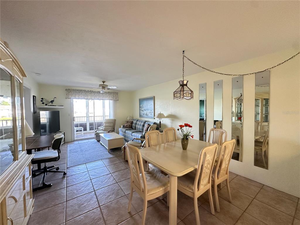A dining area and living room with tile floors, a ceiling fan, and mirrored wall panels — 12274 SW EGRET CIRCLE UNIT 2705, LAKE SUZY, FL