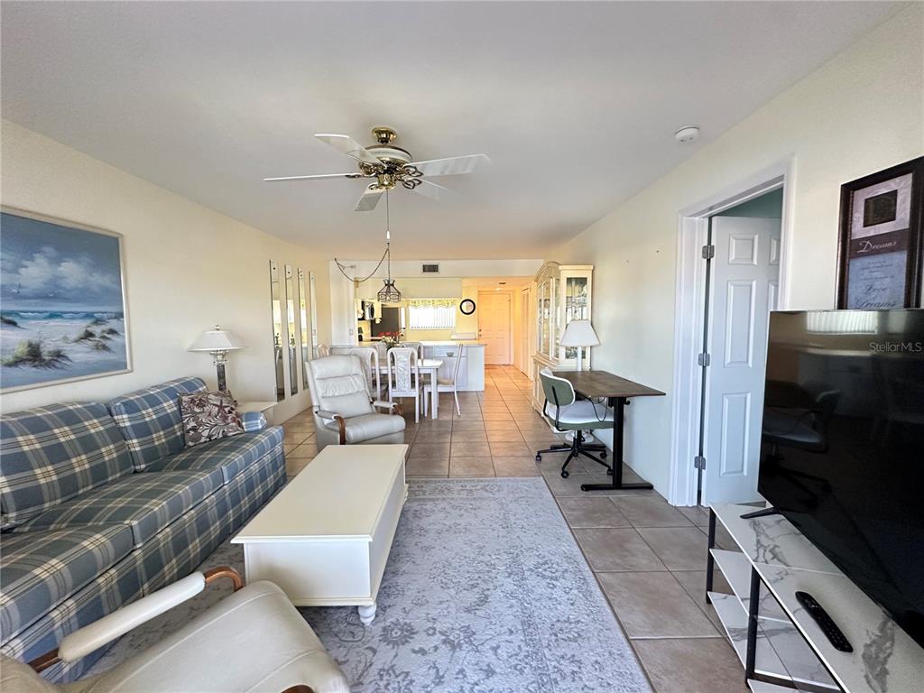 A living room with tile floors, a plaid sofa, and an open dining area — 12274 SW EGRET CIRCLE UNIT 2705, LAKE SUZY, FL
