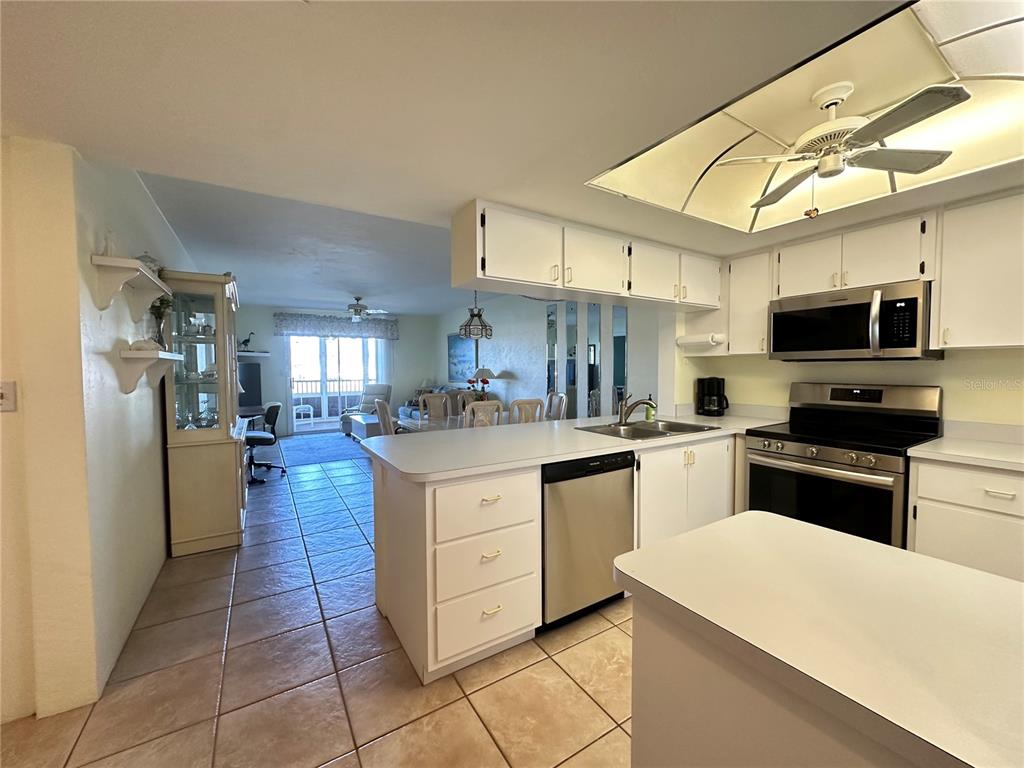 A kitchen with white cabinets and stainless steel appliances opens into a living area — 12274 SW EGRET CIRCLE UNIT 2705, LAKE SUZY, FL