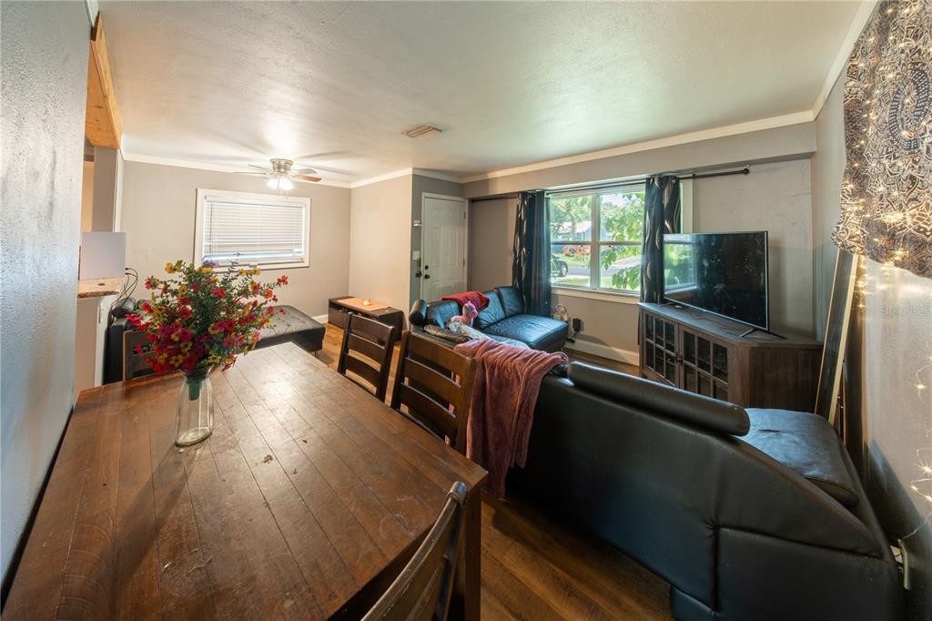 A living room and dining area with wood floors, a wooden table, and black sofas — 304 E HYDRANGIA STREET, TAMPA, FL