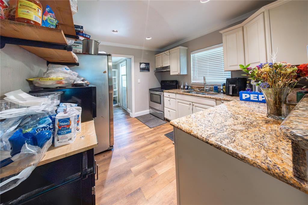 A kitchen features granite countertops, white cabinetry, stainless steel appliances, and wood-look flooring — 304 E HYDRANGIA STREET, TAMPA, FL
