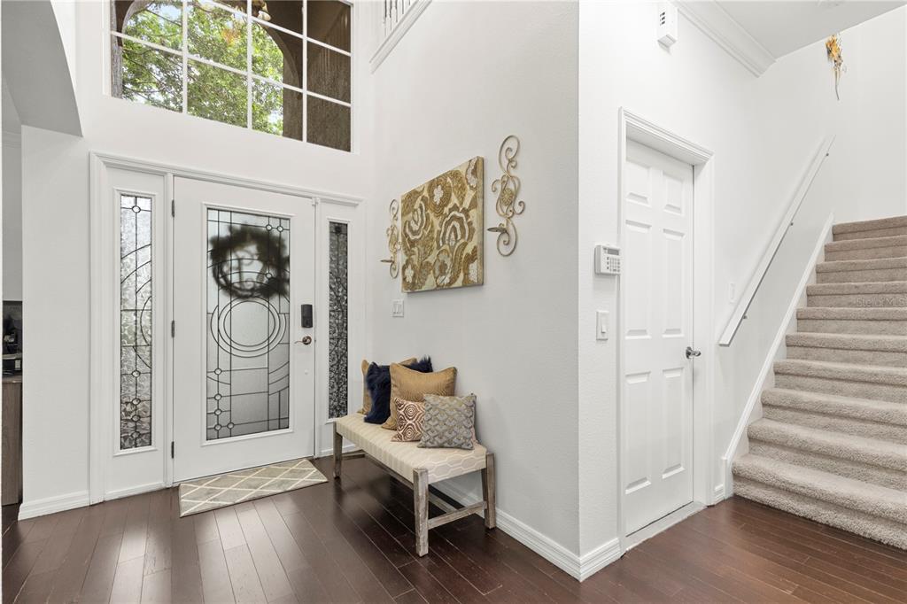 An entryway features a front door with glass panels, a wooden bench, and carpeted stairs — 6932 GRAY CATBIRD LOOP, WESLEY CHAPEL, FL
