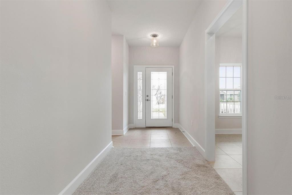 A carpeted entryway leads to a white front door with decorative glass panels — 18 RENMONT PLACE, PALM COAST, FL