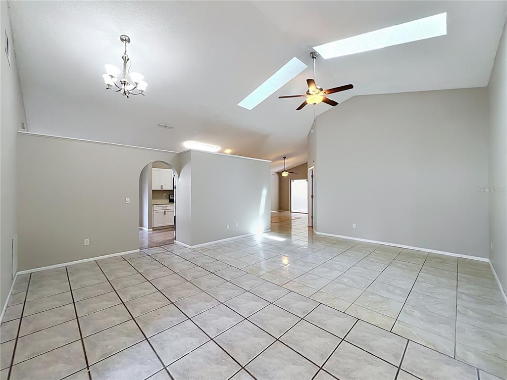 A spacious living area features vaulted ceilings, tile flooring, a ceiling fan, and skylights — 1365 CRAWFORD DRIVE, APOPKA, FL
