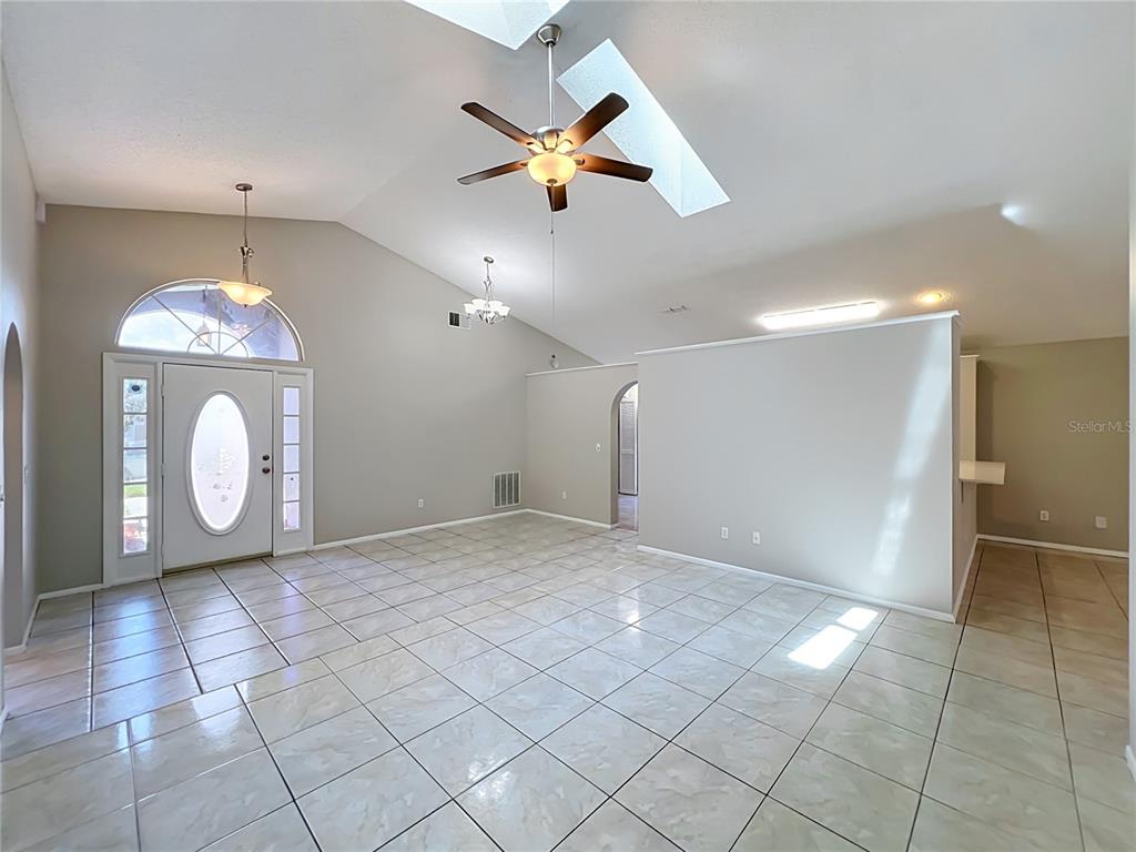 A spacious, tiled living area features a vaulted ceiling, a ceiling fan, and a skylight — 1365 CRAWFORD DRIVE, APOPKA, FL