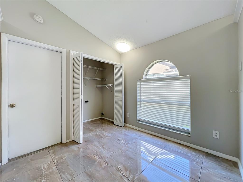A room with tiled floors, a closet with louvered doors, and an arched window — 1365 CRAWFORD DRIVE, APOPKA, FL