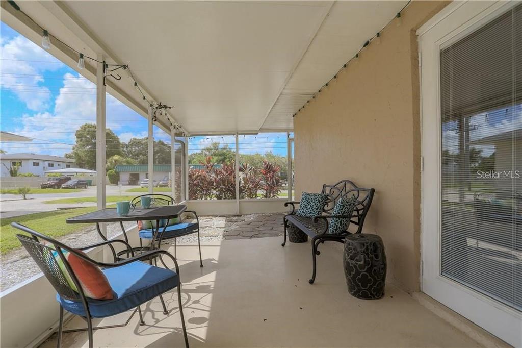 A covered, screened-in patio features a concrete floor, metal furniture, and a view of the street — 2907 HYDE PARK STREET, SARASOTA, FL