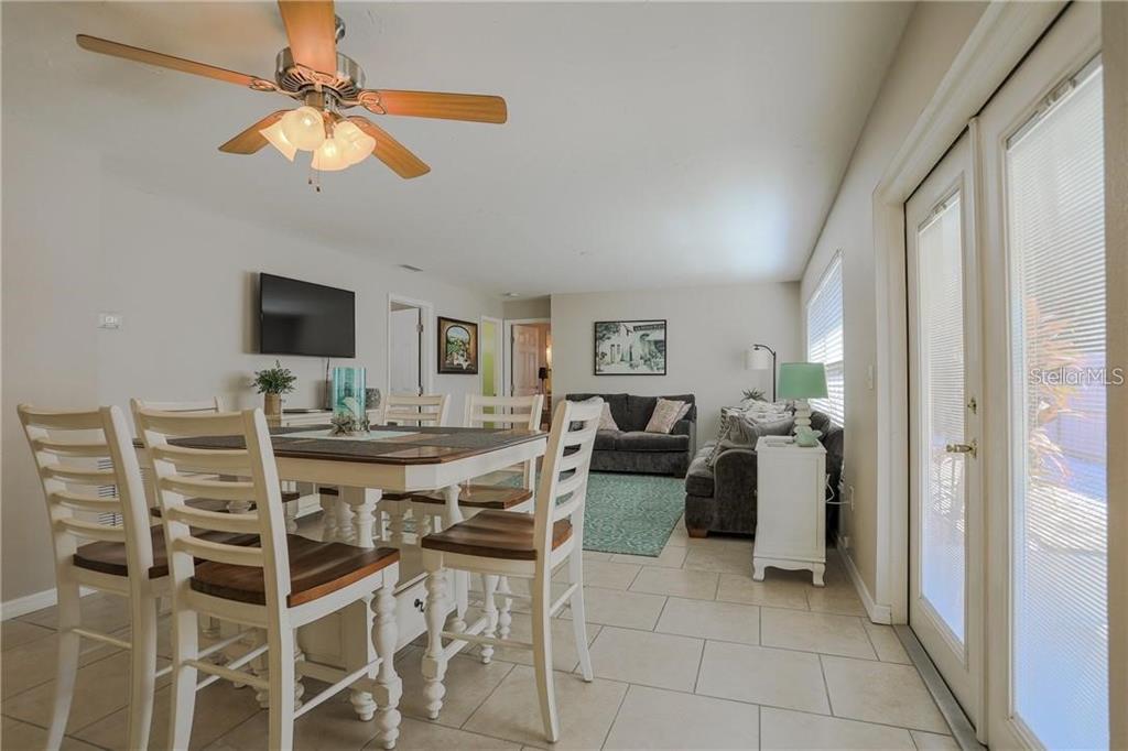 A dining area with a ceiling fan flows into a living room with tile flooring — 2907 HYDE PARK STREET, SARASOTA, FL